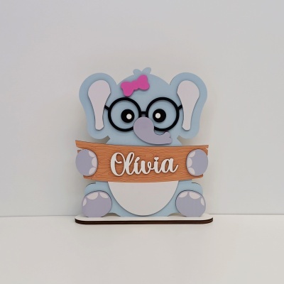 Estátua decorativa de elefante azul com laço rosa e placa com nome Olívia