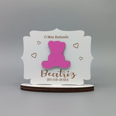 Cartão decorativo branco com ursa rosa e texto dourado para batizado