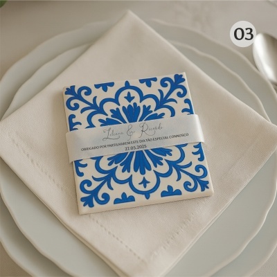 Convite de casamento azul e branco sobre guardanapo e pratos brancos