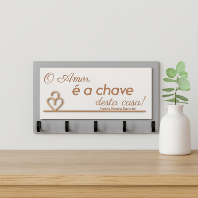 Suporte de chaves com texto decorativo e vaso branco com plantas em cima de mesa de madeira