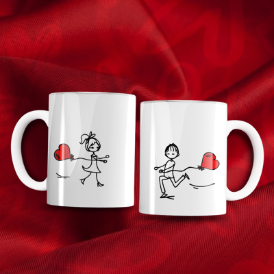 Duas canecas brancas com desenhos de menino e menina e balões de coração vermelho