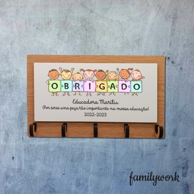 Suporte de madeira com ganchos e placa colorida com ilustração infantil e texto de agradecimento.