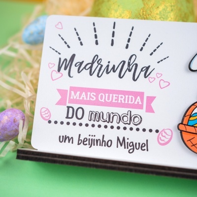 Cartão branco com texto Madrinha MAIS QUERIDA DO mundo e desenhos de corações e ovos de Páscoa.