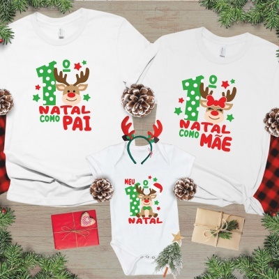 T-shirts brancas com estampados natalícios de rena e texto colorido em ambiente decorado com pinhas e presentes.