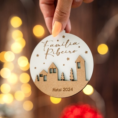 Enfeite de Natal redondo em madeira e branco com corte de casas e texto Família Ribeiro Natal 2024