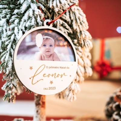 Enfeite de Natal redondo em madeira com foto de bebé e texto gravado pendurado em árvore de Natal