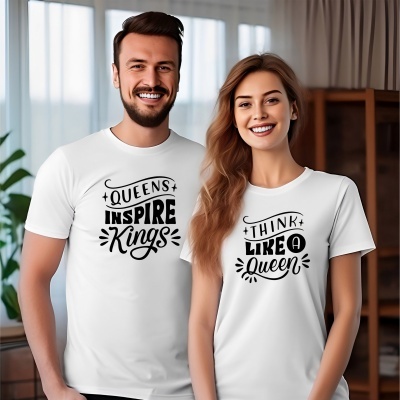 Casal a sorrir vestindo t-shirts brancas com textos motivacionais em preto no ambiente interior.