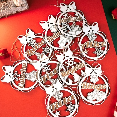 Enfeites de Natal de madeira com nomes personalizados e detalhes recortados numa superfície vermelha.