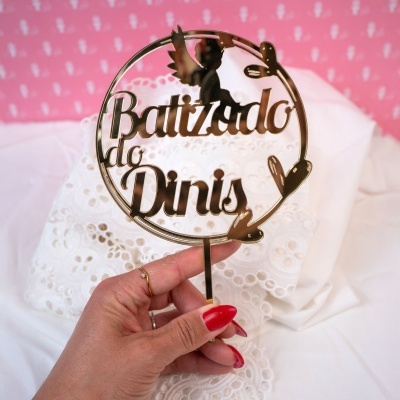 Topo de bolo metálico dourado com as palavras Batizado do Dinis