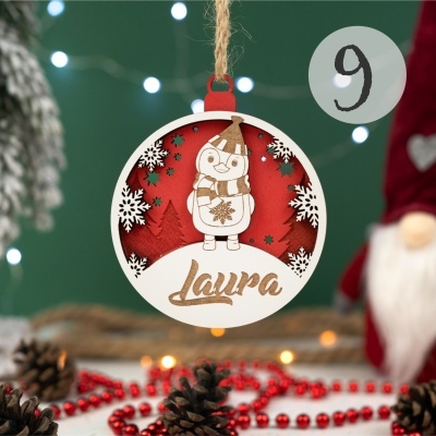 Enfeite de Natal redondo de madeira com desenho de pinguim e o nome Laura