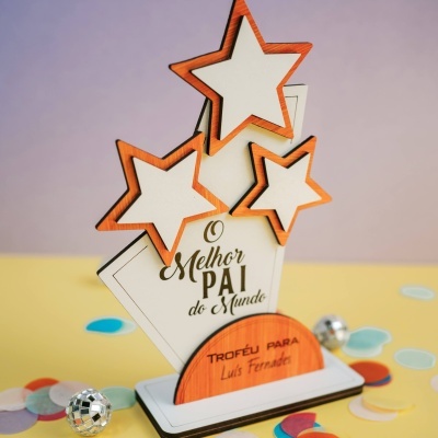 Troféu em forma de estrela com texto O Melhor Pai do Mundo numa base branca com confetis