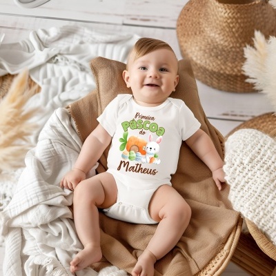 Bebé vestindo body branco com estampa de Páscoa colorida sentado em almofada castanha em ambiente decorado