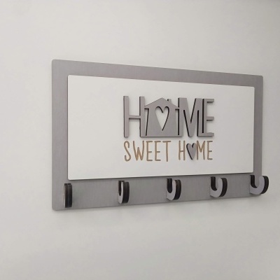 Cabide de parede cinzento e branco com texto decorativo e cinco ganchos.