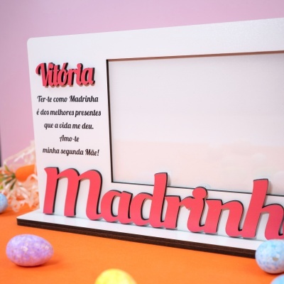 Moldura branca com palavra em madeira vermelha e preta Madrinha e texto em português em fundo rosa