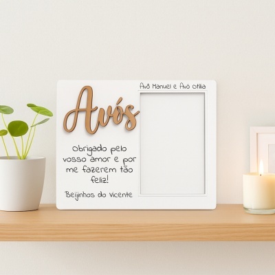 Moldura branca para foto com palavra Avós em madeira e texto de agradecimento, planta e vela em prateleira.