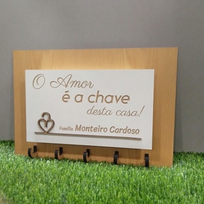 Placa de madeira com suporte para chaves e texto decorativo em português