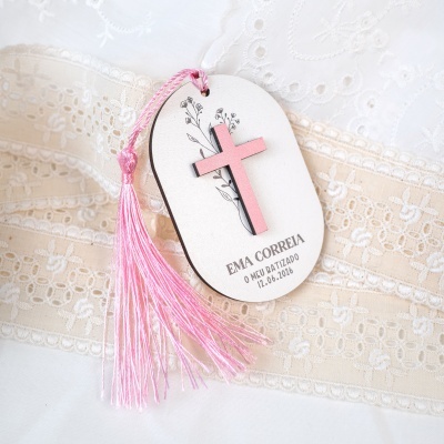 Marcador de livro branco com cruz cor-de-rosa e tassel rosa sobre tecido bordado branco