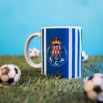 Caneca com brasão FCP e riscas azuis e brancas sobre relva artificial
