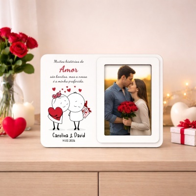Moldura branca com foto de casal e texto romântico numa mesa de madeira com flores e presentes.