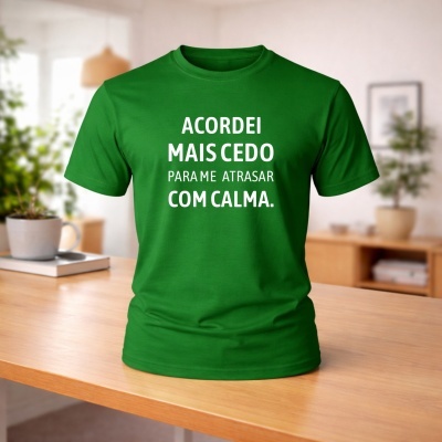 T-shirt verde com texto em branco sentado numa mesa de madeira numa sala com plantas.