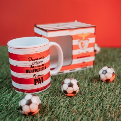 Caneca branca e vermelha com texto para pai benfiquista junto a caixa com emblema SL Benfica em relva artificial