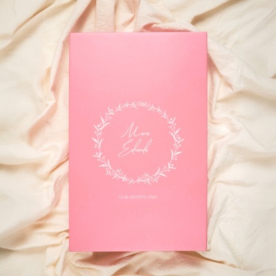 Caixa rosa com design minimalista e texto branco colocada sobre tecido bege