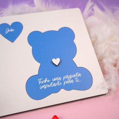 Cartão decorativo com urso e coração azuis e texto em branco sobre fundo lilás