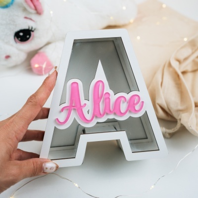 Espelho em forma de letra A com texto Alice em relevo rosa