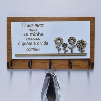 Cabideiro de parede com ganchos e placa decorativa com texto em português e flores de madeira