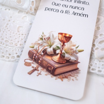 cartão religioso com cálice dourado, flores e livros sobre renda branca