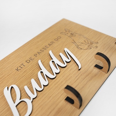 Placa de madeira com letras em relevo, desenho de cão e texto KIT DE PASSEAR DO