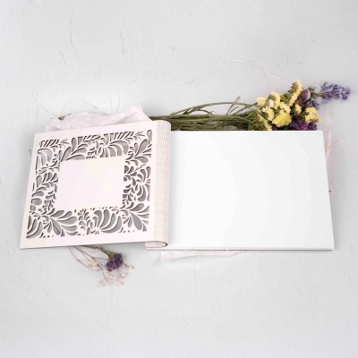 Livro branco com capa recortada e flores amarelas e roxas junto