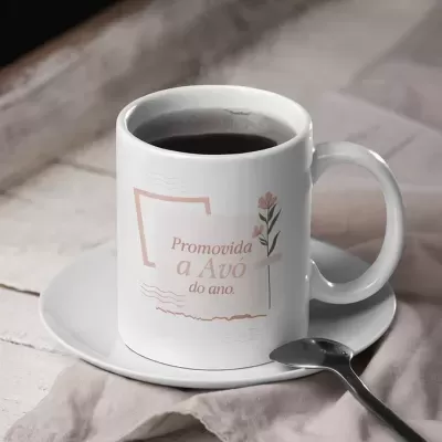 Caneca cerâmica branca com texto e flores, café dentro, pires branco e colher, sobre pano e madeira clara