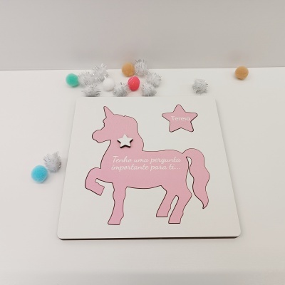 Tapete com relevo de unicórnio rosa e estrela rosa com nome Teresa num fundo branco, com bolas de felpa coloridas ao redor