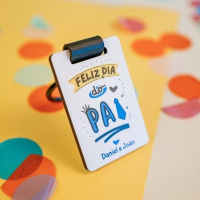 Clipe de secretária com placa escrita Feliz Dia do Pai e nomes Daniel e João em fundo amarelo com formas coloridas