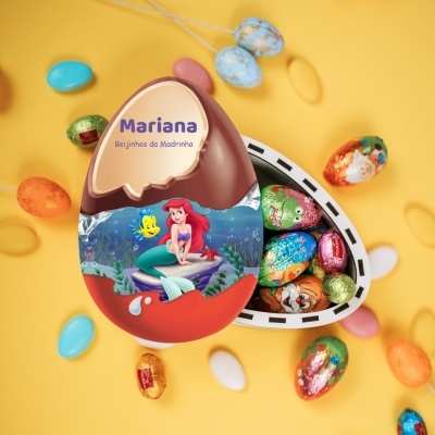 Ovo de chocolate decorado com personagem Ariel e texto personalizado, aberto com chocolates dentro sobre fundo amarelo.