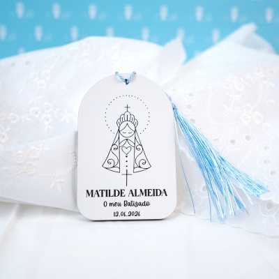 Cartão de batizado branco com desenho religioso, fita azul e tecido branco bordado.