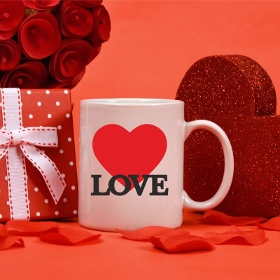 Caneca branca com coração vermelho e texto LOVE, caixa de presente vermelha com bolinhas brancas e fita, rosas vermelhas e coração brilhante vermelho
