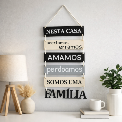 Placa decorativa de madeira com texto em português pendurada numa parede cinzenta ao lado de uma lâmpada, vasos com plantas e livros.