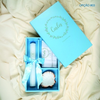 Conjunto em caixa azul com vela, lenço e concha sobre tecido bege