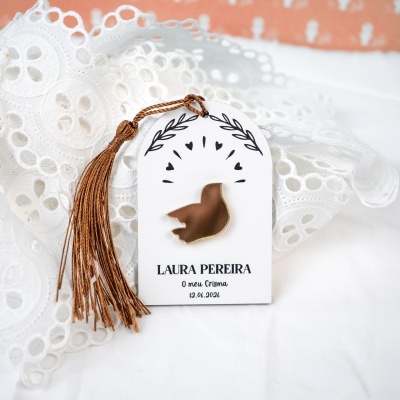 Etiqueta com pássaro dourado e tassel castanho sobre tecido branco rendado