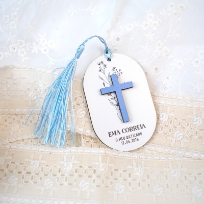 Marcador de página com cruz azul e tassel azul sobre tecido bordado branco e bege