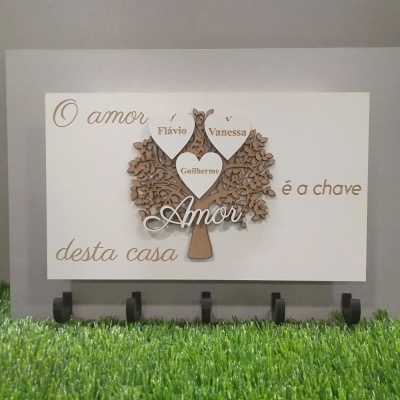 Quadro decorativo com árvore em madeira e corações com nomes e texto em português.