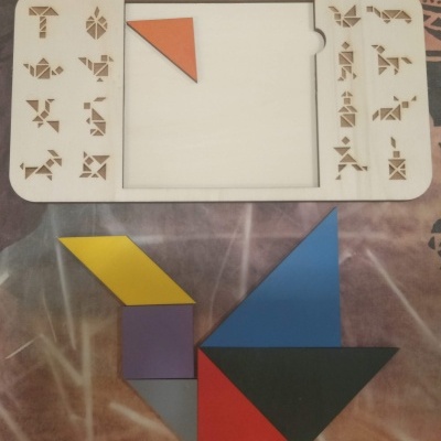 Jogo de tangram em madeira com peças coloridas sobre pano