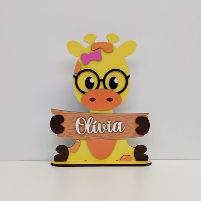 Decoração de girafa amarela com laço rosa, óculos pretos e placa de madeira Olívia