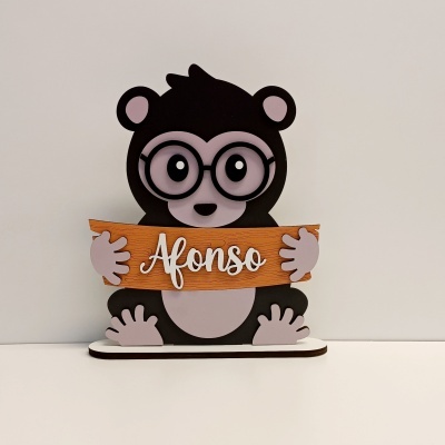 Objeto decorativo de urso castanho segurando placa com nome Afonso