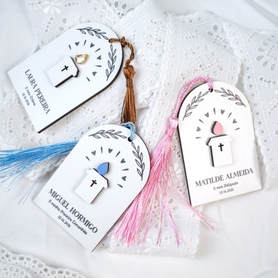 Etiquetas decorativas religiosas com cruzes e franjas coloridas sobre tecido branco com renda
