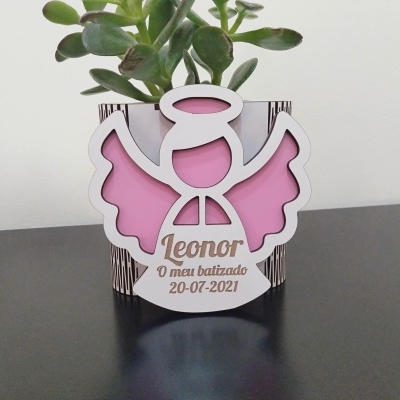 Vaso com planta verde em vaso decorativo com anjo branco e rosa e texto celebrando batizado.