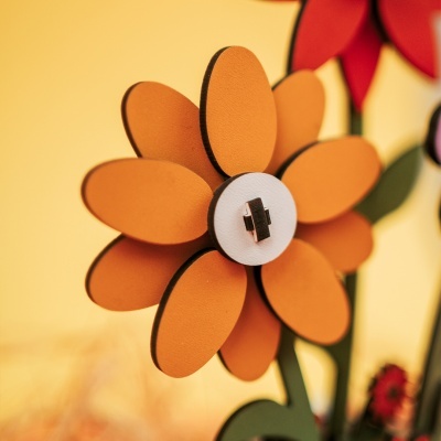 Flor decorativa em madeira com pétalas laranja e centro branco