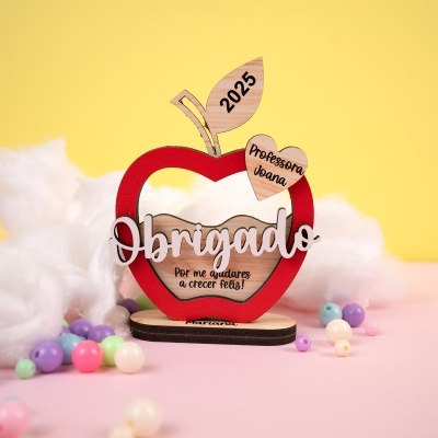 Figura decorativa em madeira com forma de maçã vermelha e textos gravados